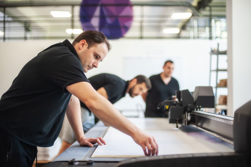 three men working together on a large format printer